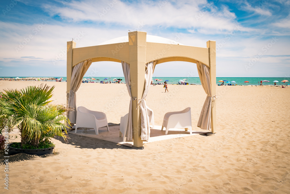 Gazebo with white chairs on the beach.