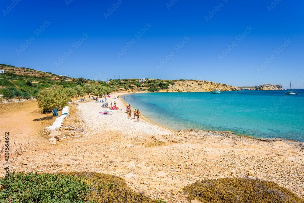 Pretty sunny coast view to a cozy holiday bay with crystal clear blue water sandy beach for sunbathing and some boats cruising fishing, Lipsi Island, Patmos, Dodecanese, Greece Pretty sunny coast view to a cozy holiday bay with crystal clear blue water sandy beach for sunbathing and some boats cruising fishing, Lipsi Island, Patmos, Dodecanese, Greece