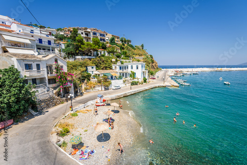 Beautiful sunny greek village town white house and harbor view to the aegean blue sea with crystal clear water and fishing boats cruising yacht white houses, Ikaria Island, Evdilos, Sporade, Greece © Thomas Jastram