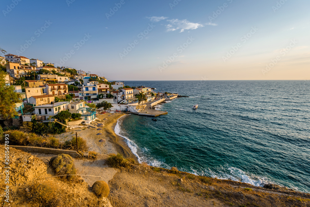 Beautiful colorful purple greek sunset sunrise coast view to a small greek town village with harbour fishing boats blue sea with crystal clear water, Ikaria Island, Armenisits, Sporades, Greece