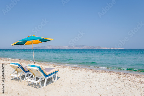 Beautiful sunny coast view to the greek beach mediterranean blue sea with crystal clear water and pure sandy beach while some tourists are sunbathing and relaxing in Marmari Tigaki