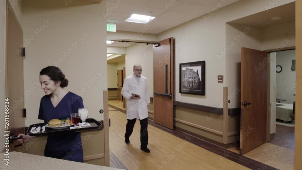 Medium shot of nurse taking food into a room Medium shot of nurse taking food into a room