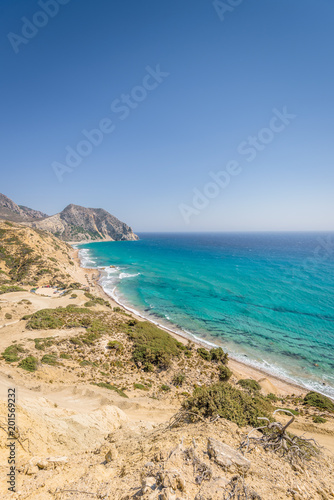 Fototapeta Naklejka Na Ścianę i Meble -  Beautiful sunny coast view to the greek mediterranean blue sea with crystal clear water and pure sandy beach empty place with some mountains rocks surrounded, Kos, Dodecanese Islands, Greece