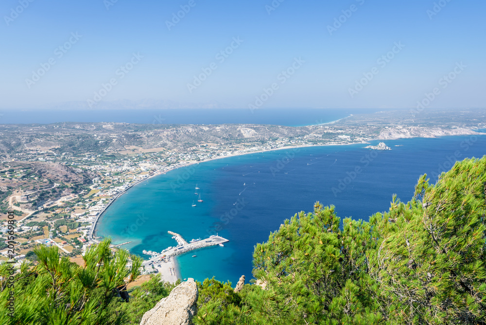 Beautiful sunny coast view to the greek mediterranean blue sea with crystal clear water and pure sandy beach empty place with some mountains rocks surrounded, Kos, Dodecanese Islands, Greece Beautiful sunny coast view to the greek mediterranean blue sea with crystal clear water and pure sandy beach empty place with some mountains rocks surrounded, Kos, Dodecanese Islands, Greece