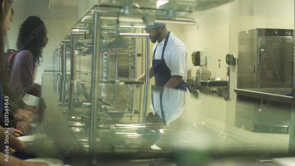 Medium shot kitchen staff serving food for high schoolers