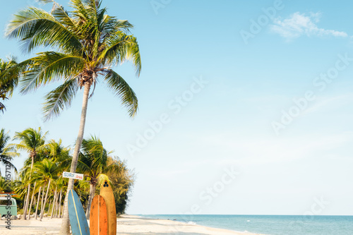 Fototapeta Naklejka Na Ścianę i Meble -  Landscape of coconut palm tree on tropical beach in summer. beach sign for surfing area. Vintage effect color filter.