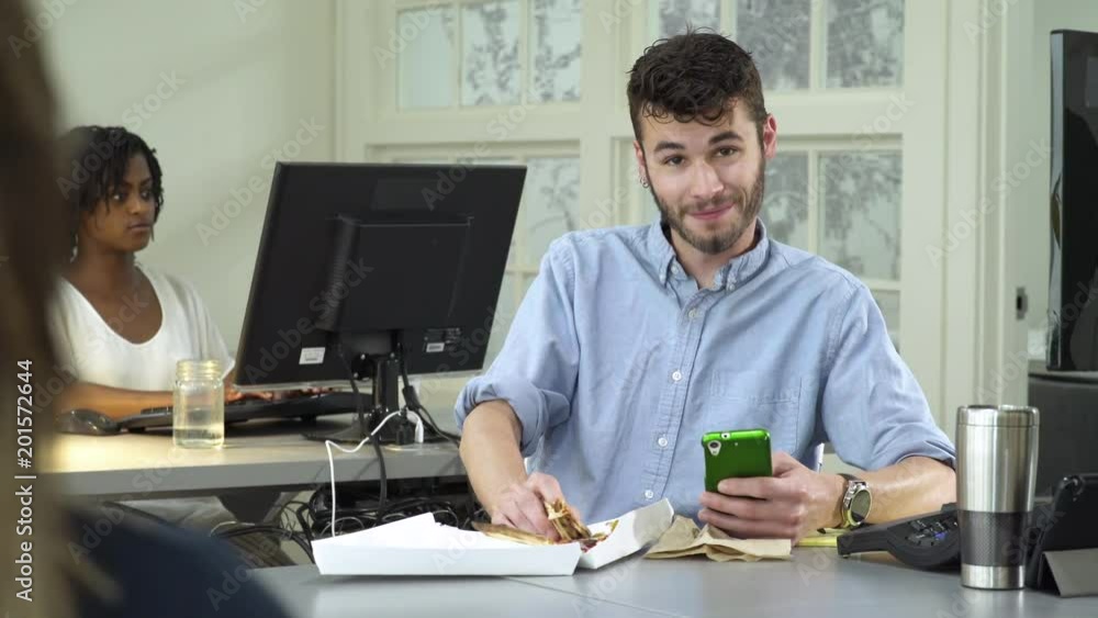 Young man eating while working in an office Young man eating while working in an office