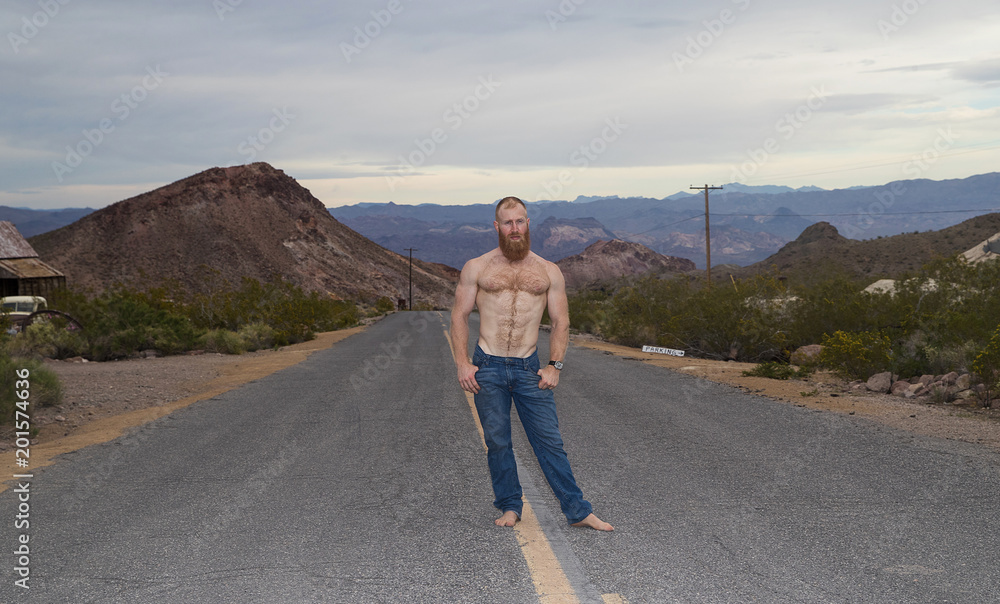 Shirtless, barefoot man alone on a desert highway Shirtless, barefoot man alone on a desert highway