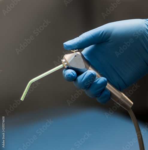 Dental air water syringe being held by hand with blue latex glove. 