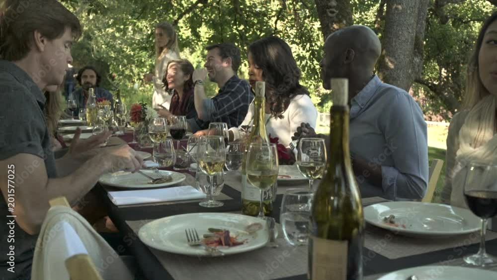 Friends eating at a gathering in a yard Friends eating at a gathering in a yard