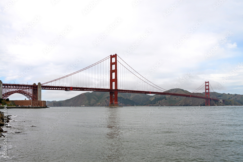 Golden Gate Bridge spans almost two miles across the Golden Gate, the narrow strait where San Francisco Bay opens to meet the Pacific ocean. Fort Mason tucked in on the left side under the arch.