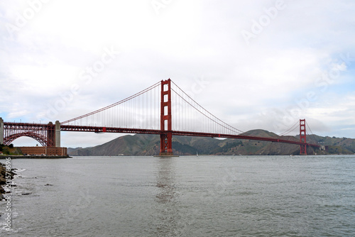 Golden Gate Bridge spans almost two miles across the Golden Gate  the narrow strait where San Francisco Bay opens to meet the Pacific ocean. Fort Mason tucked in on the left side under the arch.