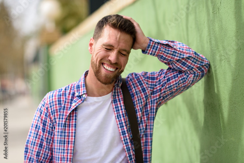 Attractive young man laughing outdoors. Lifestyle concept.