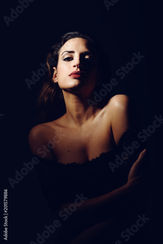 Foto Young brunette woman in black lingerie in chiaroscuro lighting