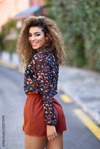 Happy young arabic woman with black curly hairstyle.