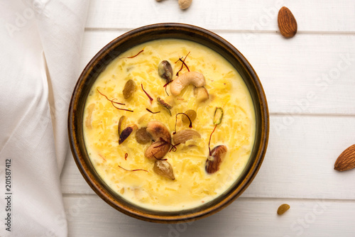 kheer or rice pudding is an Indian dessert in a brown terracotta bowl with dry fruits toppings
 photo