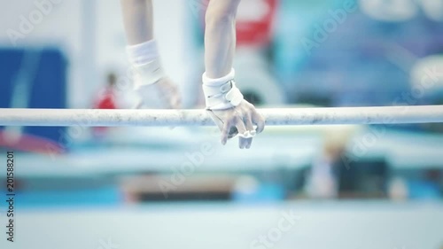 Athletic woman gymnasts performing on the bar at the championship photo