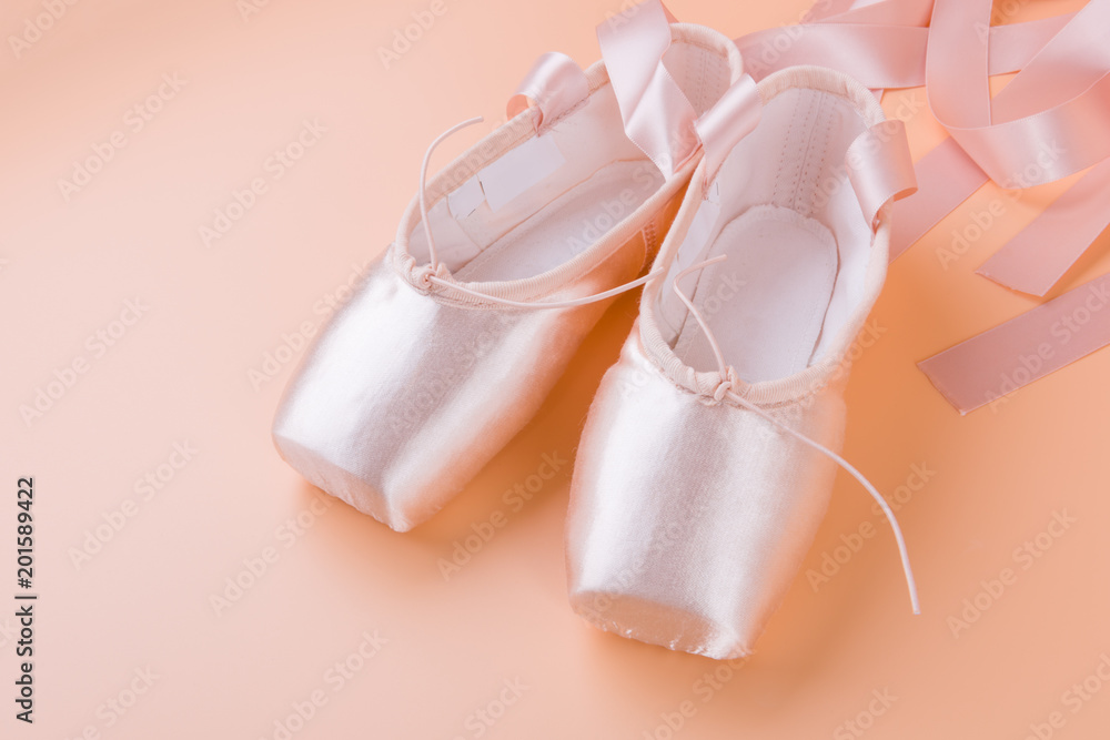 New pair of ballet shoes with ribbons on yellow background New pair of ballet shoes with ribbons on yellow background