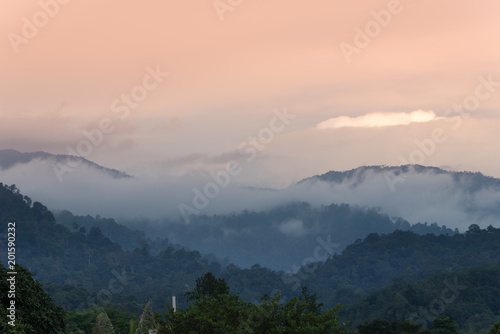 the mountains of BANJARAN TITIWANGSA surrounded by white clouds near the sunset