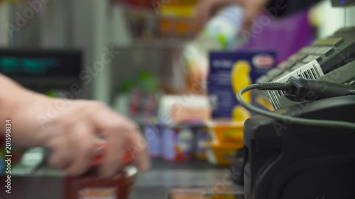 Close up check out counter. Senior female hands working on cash register in the supermarket