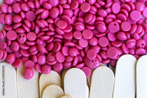 depilatory pearly pink  solid wax beans and wooden stick background photo