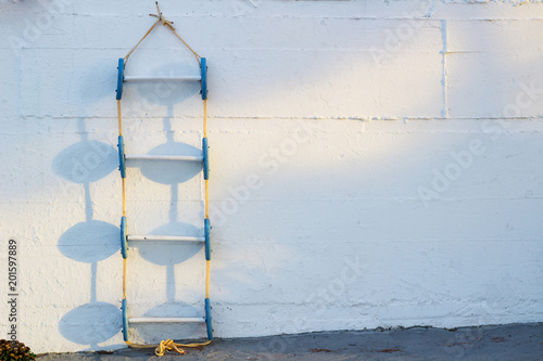 Conceptional background of blue marine ladder leaning against white wall © Vera Verano