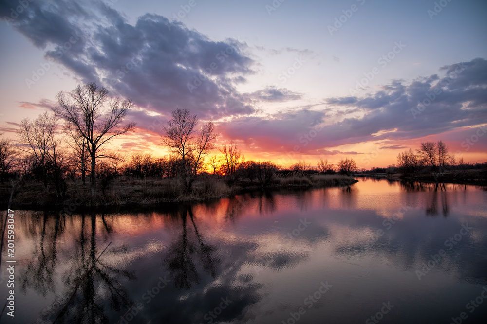 River during the sunset quietly flowing flows through the spring forest in early April