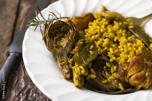 Plato de paella con alcachofas y carne
