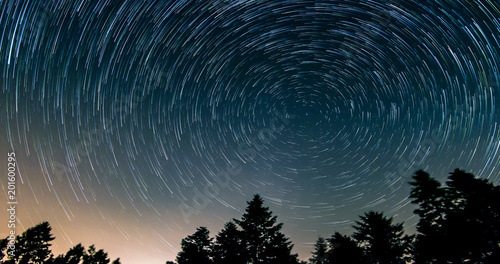 Star trails over the night sky - comet mode, Time lapse of star trail, pine trees in the foreground, Avala, Belgrade, Serbia. The night sky is astronomically accurate.