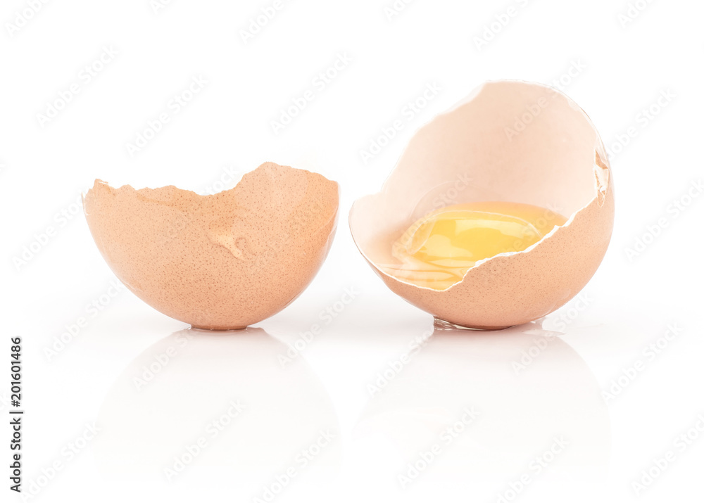 One cracked brown chicken egg isolated on white background raw yolk in two broken eggshell halves. One cracked brown chicken egg isolated on white background raw yolk in two broken eggshell halves.