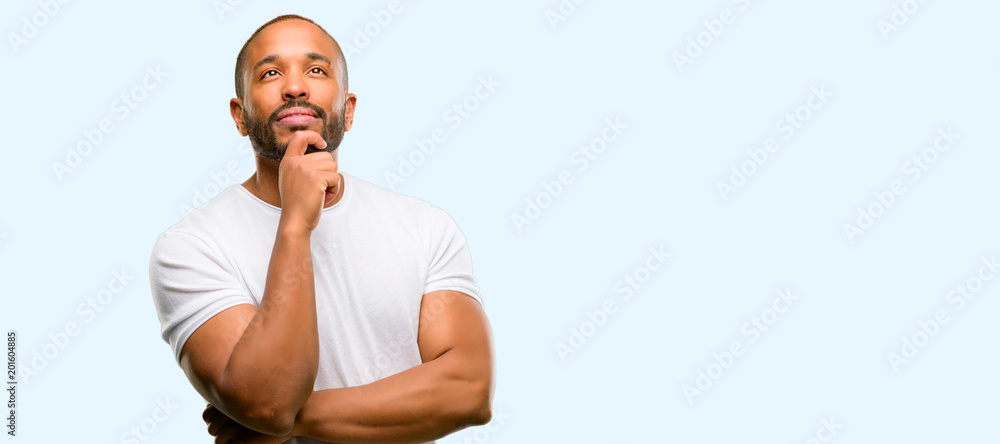 African american man with beard thinking and looking up expressing doubt and wonder isolated over blue background African american man with beard thinking and looking up expressing doubt and wonder isolated over blue background