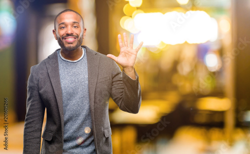 African american man with beard raising finger, is the number five at night