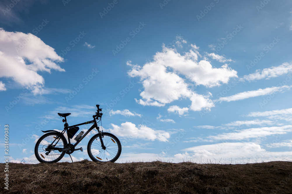 Bike silhouette in blue sky with clouds. symbol of independence and freedom