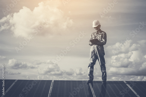 engineers operating and check generating power of solar power plant on solar rooftop; technician in industry uniform on level of job description at industrial