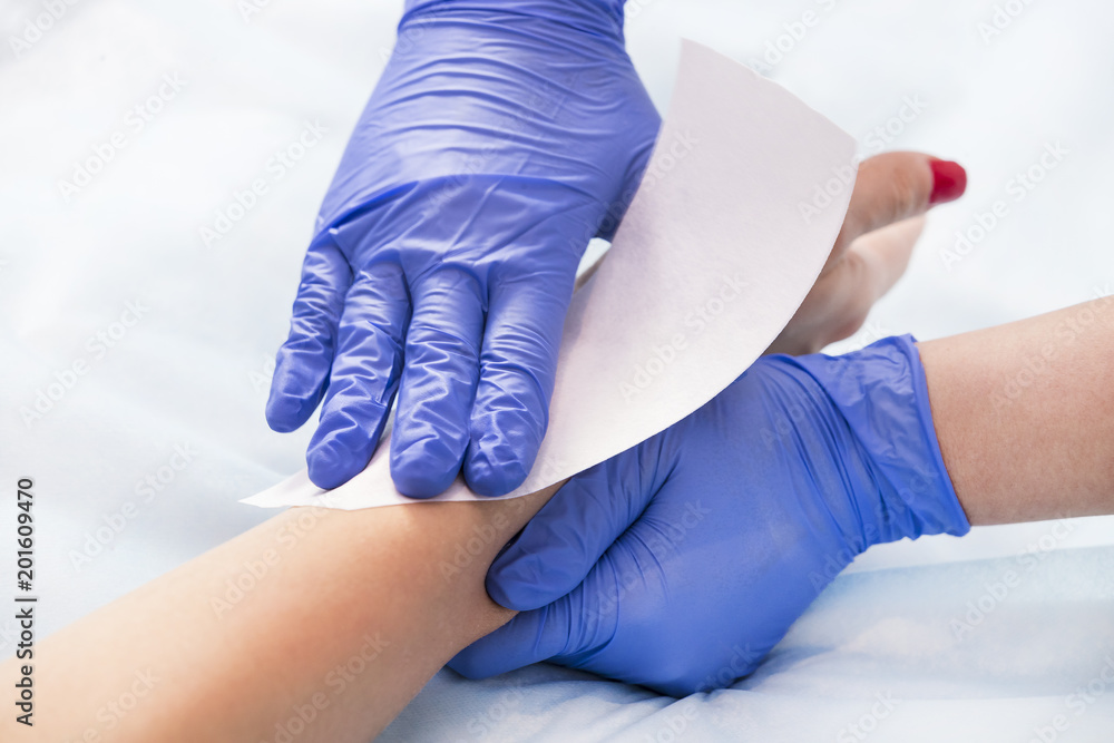 The process of classical wax depilation of female limbs in the beauty salon. 