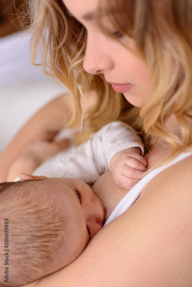 Foto de Breastfeeding baby close up. Pretty mother holding her newborn  child. Mom nursing baby. Beautiful woman and new born relax at home. Blondе  mother breast feeding baby. do Stock