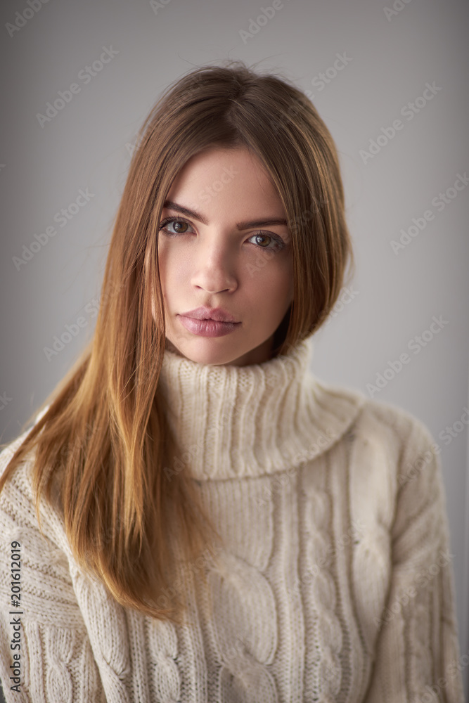 Concept: professional fashion lifestyle. Beautiful model posing in studio during classic test shooting wearing white sweater. Woman show poses and emotions. Portrait calm and serious Concept: professional fashion lifestyle. Beautiful model posing in studio during classic test shooting wearing white sweater. Woman show poses and emotions. Portrait calm and serious