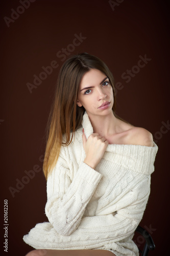 Concept: professional fashion lifestyle. Beautiful model posing in studio during classic test shooting wearing white sweater and white lingerie. Woman show poses and emotions.