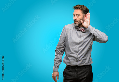Middle age man, with beard and bow tie holding hand near ear trying to listen to interesting news expressing communication concept and gossip