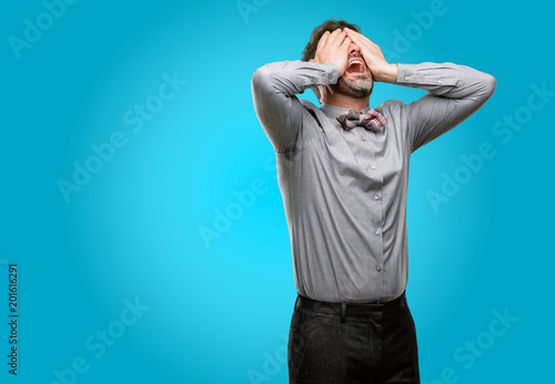 Middle age man, with beard and bow tie stressful keeping hands on head, tired and frustrated