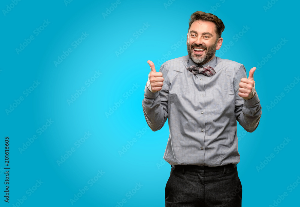 Middle age man, with beard and bow tie smiling broadly showing thumbs up gesture to camera, expression of like and approval Middle age man, with beard and bow tie smiling broadly showing thumbs up gesture to camera, expression of like and approval