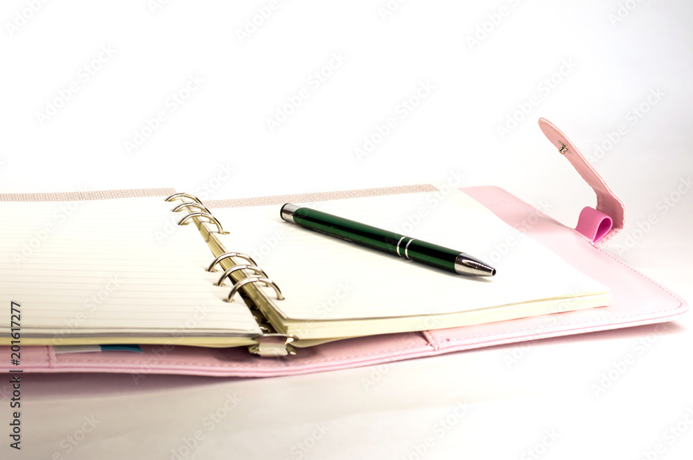 pink notebook with a ballpoint pen lying on white background pink notebook with a ballpoint pen lying on white background
