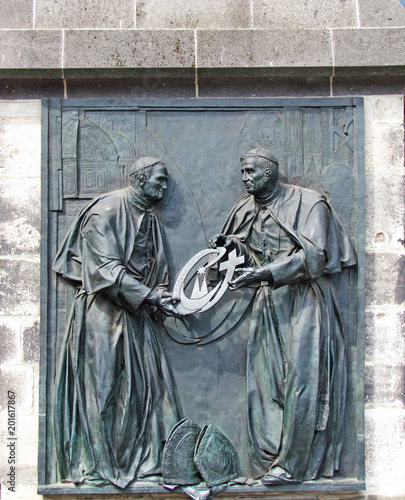 Relief in honor of the meeting of Pope Ioannes Paulus PP. II and Cardinal Joseph Alois Ratzinger in Cologne. It is installed on the outer wall of the Cologne Cathedral. Germany, Cologne, August 2013 photo