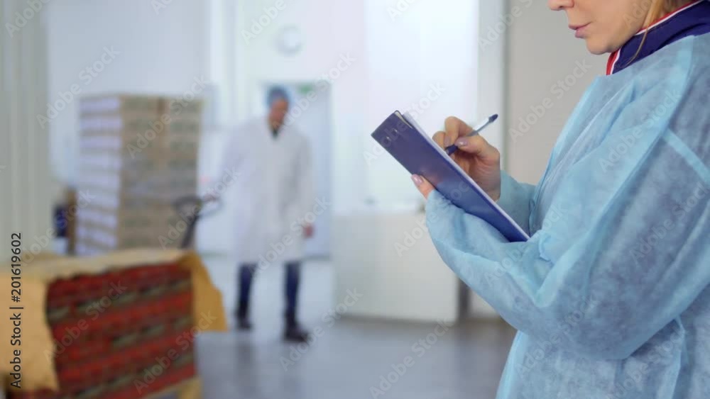 Woman makes notes in her report about work of factory Woman makes notes in her report about work of factory