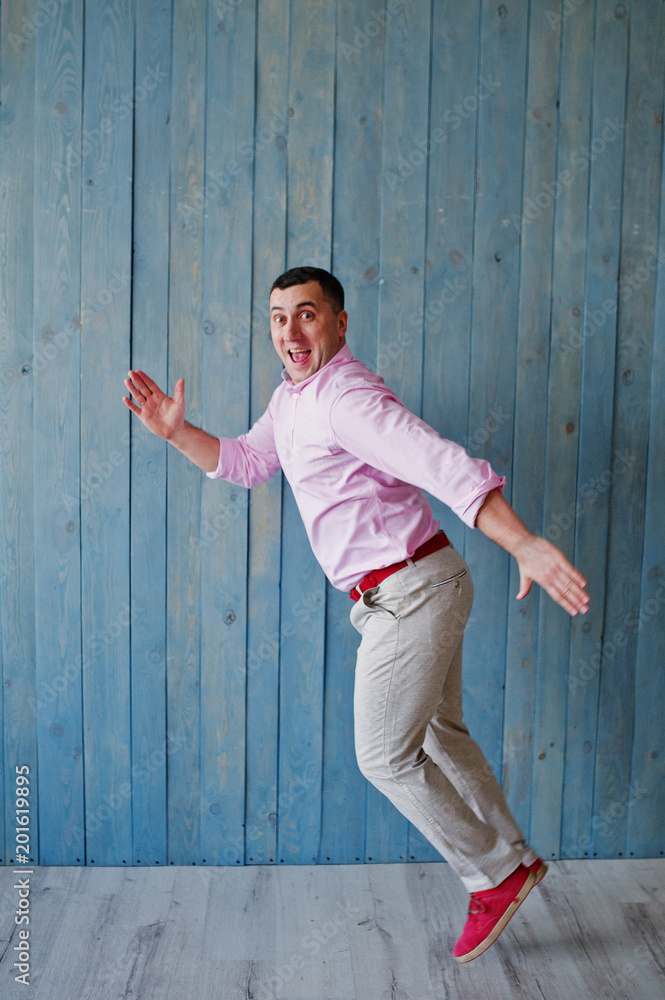 Studio portrait of man in pink shirt against wooden background. Studio portrait of man in pink shirt against wooden background.