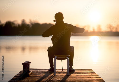 Cello cellist musician playing music as professional in summer while sunset, very relaxing