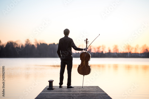 Cello cellist musician playing music as professional in summer while sunset, very relaxing