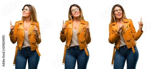 Beautiful young woman happy and surprised cheering pointing up over white background