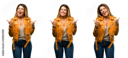 Beautiful young woman smiling broadly showing thumbs up gesture to camera  expression of like and approval over white background