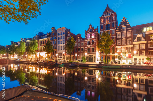 Amsterdam canal Herengracht with typical dutch houses and their reflections during morning blue hour, Holland, Netherlands.